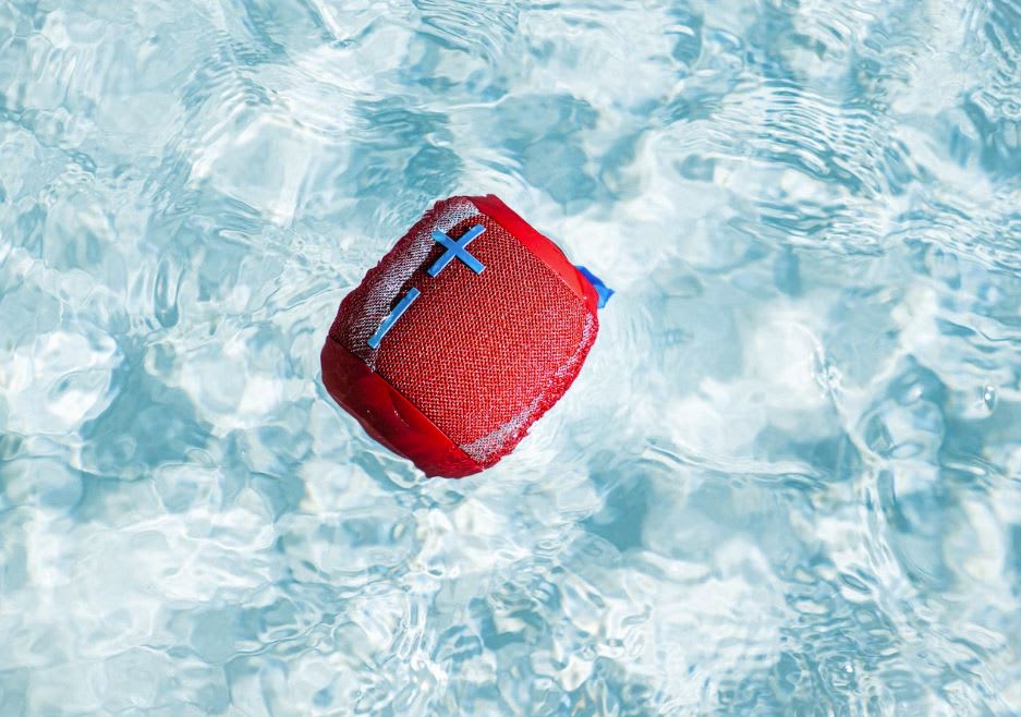 Red second-hand waterproof speaker, floating in the middle of a swimming pool