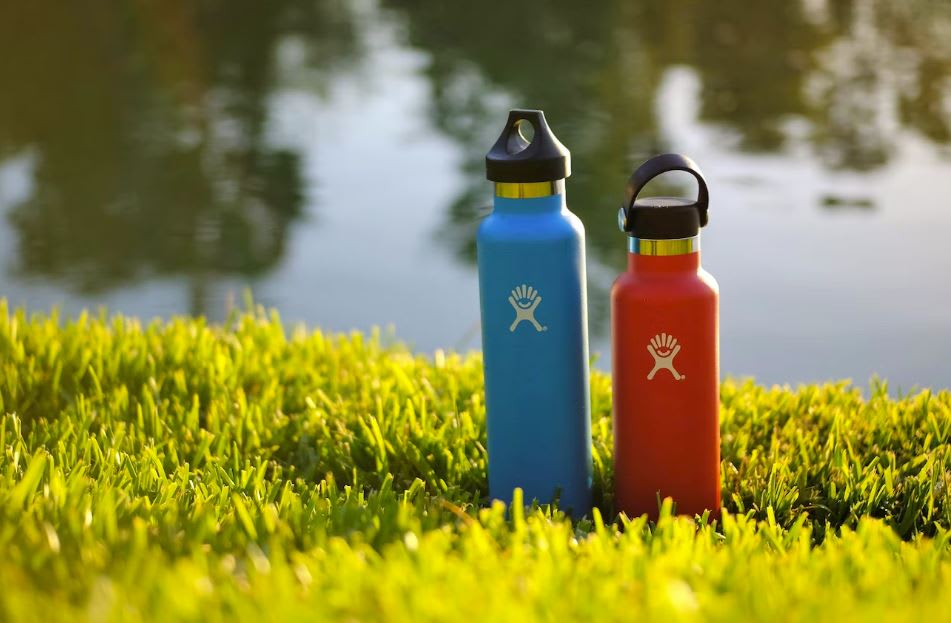 Blue and red water bottles on grass by river