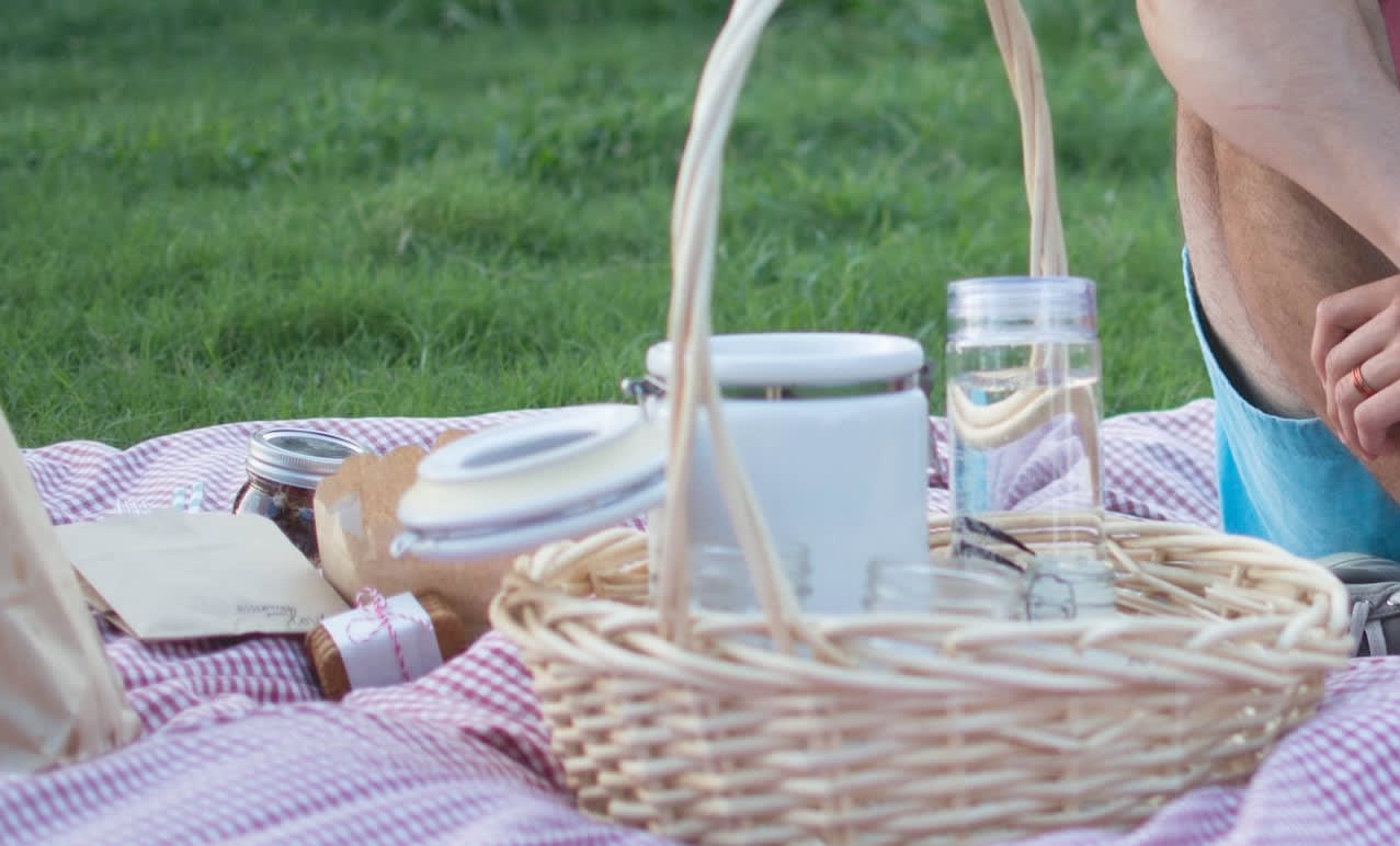 Person sitting in a park on a blanket whilst enjoying a picnic