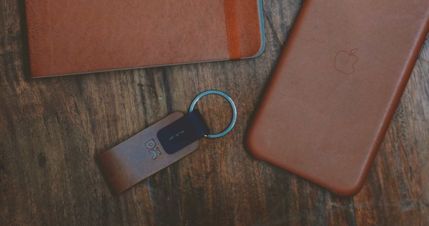 Brown keychain beside phone and notebook