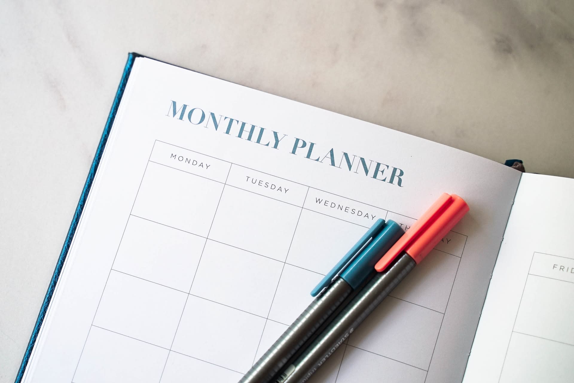 Close up of a monthly planner with pens on top of it