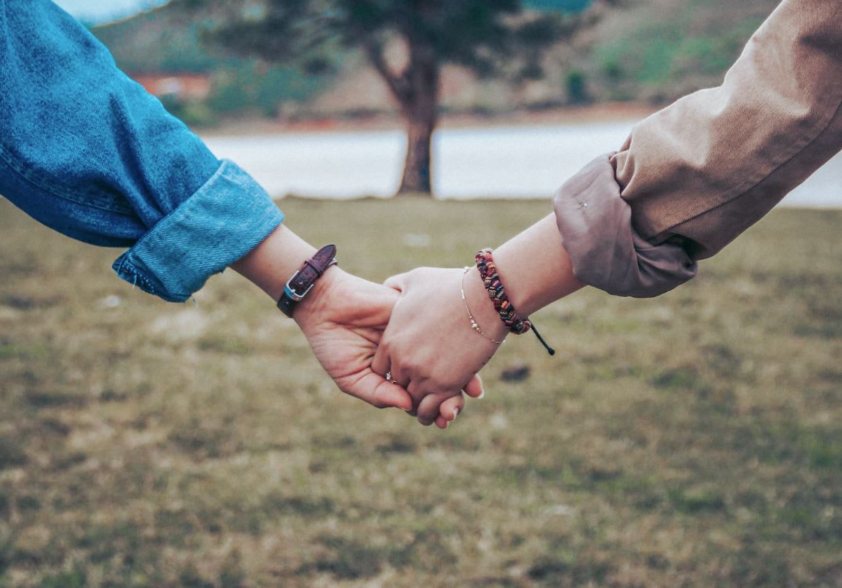 Couple holding hands in front of a tree