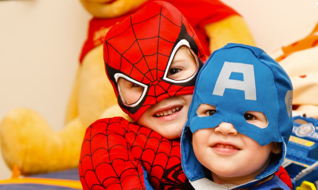Two kids hugging wearing superhero costumes