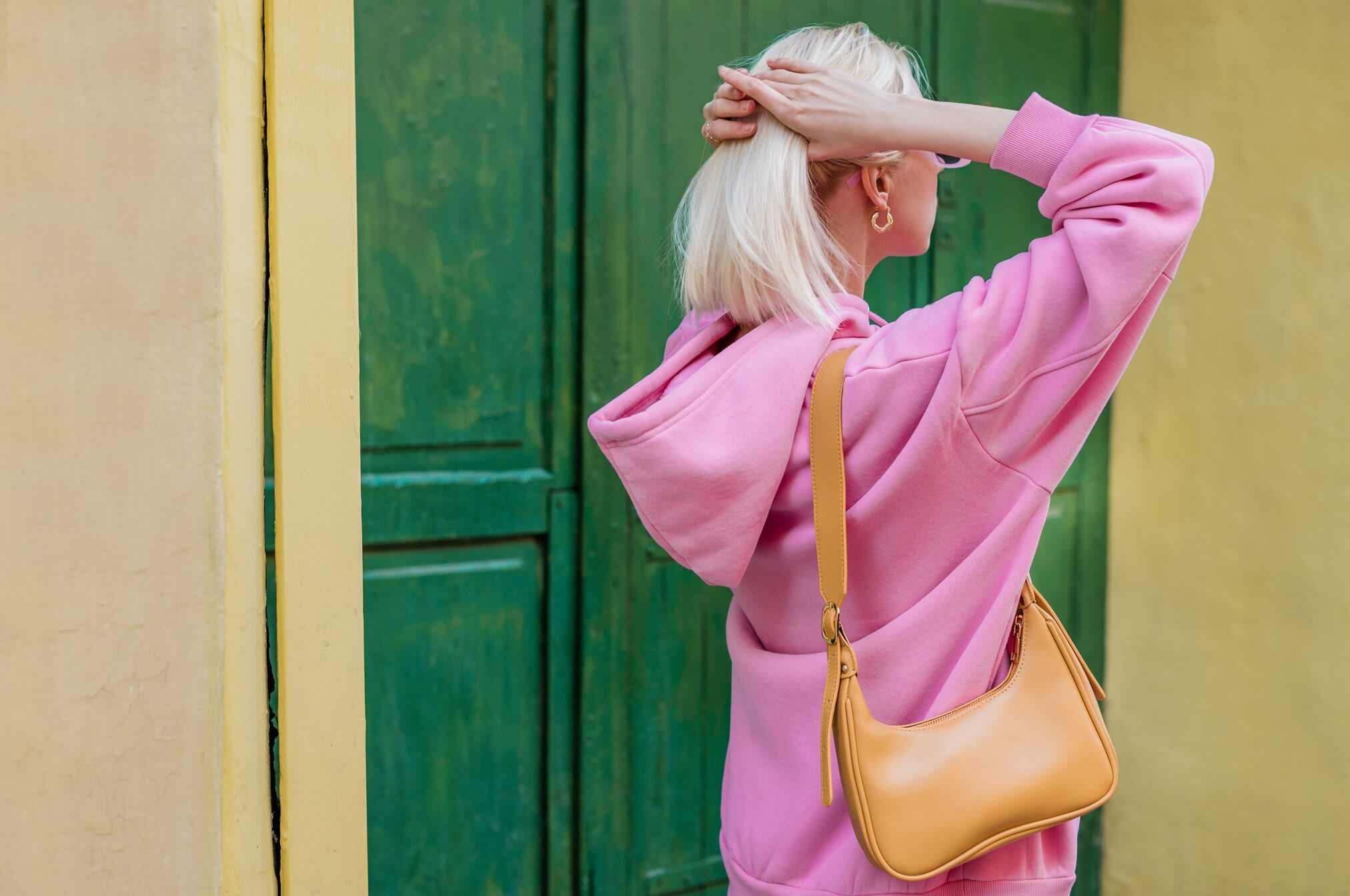 Blonde girl wearing bright pink second-hand hoodie and gold hoop earrings