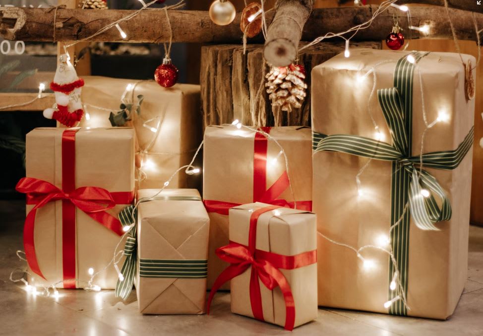 Selection of presents under the tree with brown wrapping, ribbon and Christmas lights