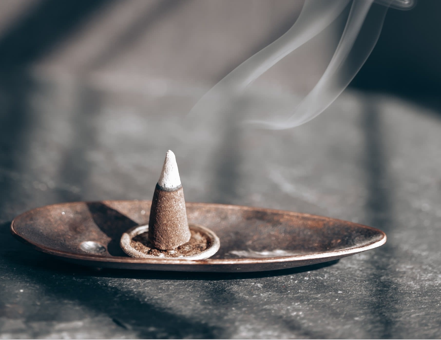 Burning used incense cone on brass dish