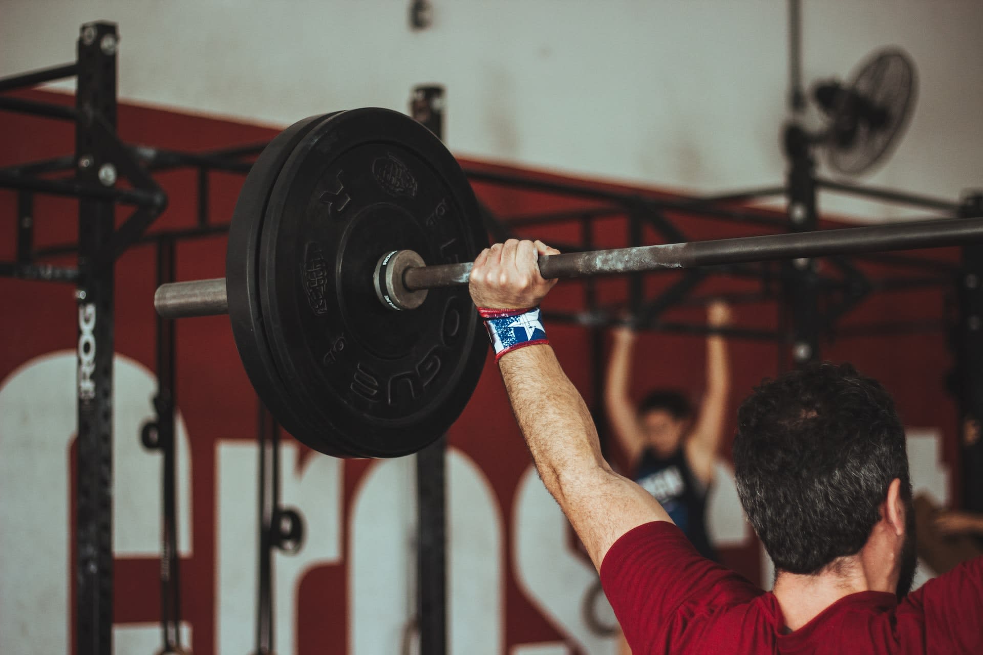 Man wearing lifting straps holding up weights