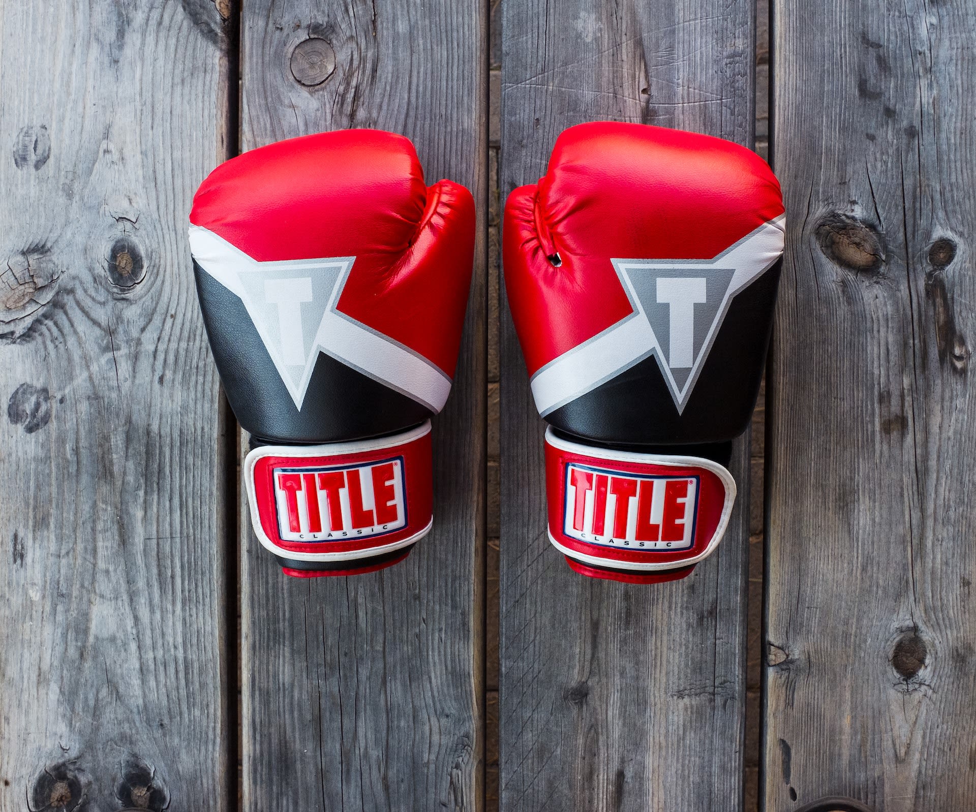 Pair of used boxing gloves on wooden floorboards