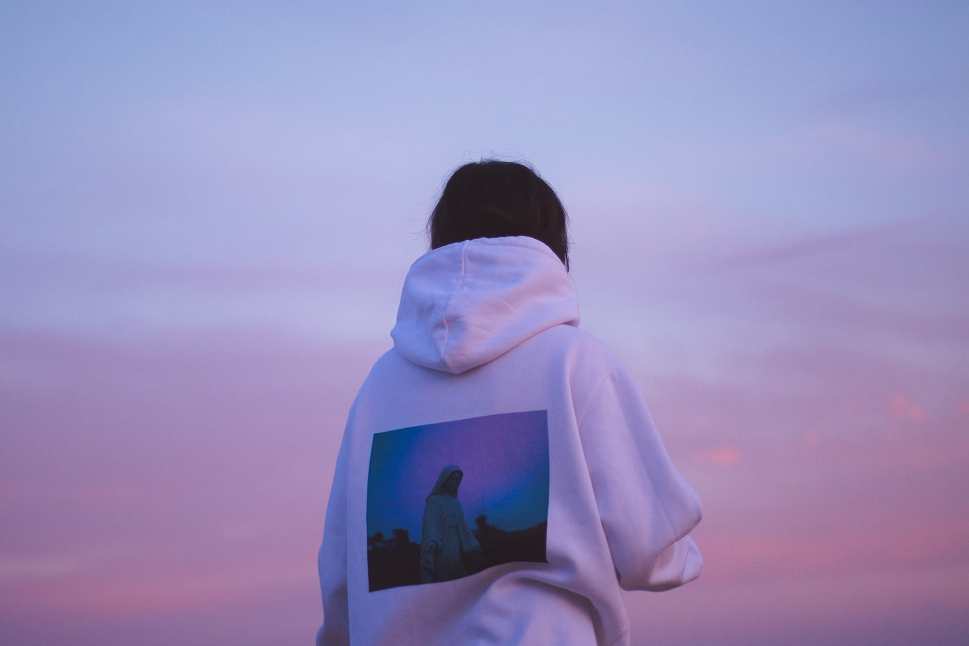 Woman wearing a pre-loved white hoodie with graphic print on the back