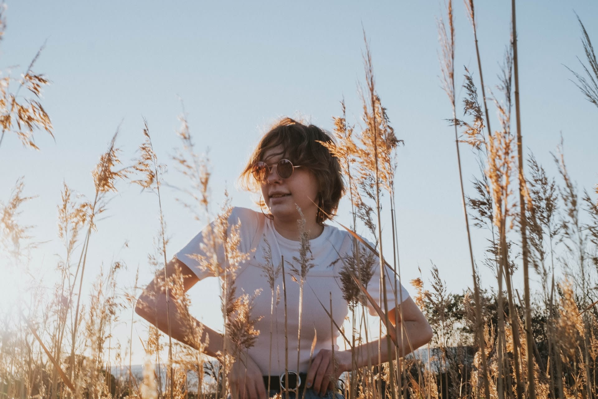 Woman in plain white tee standing behind some wheat in a field