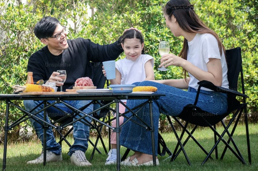 a family sat on camping chairs at a picnic