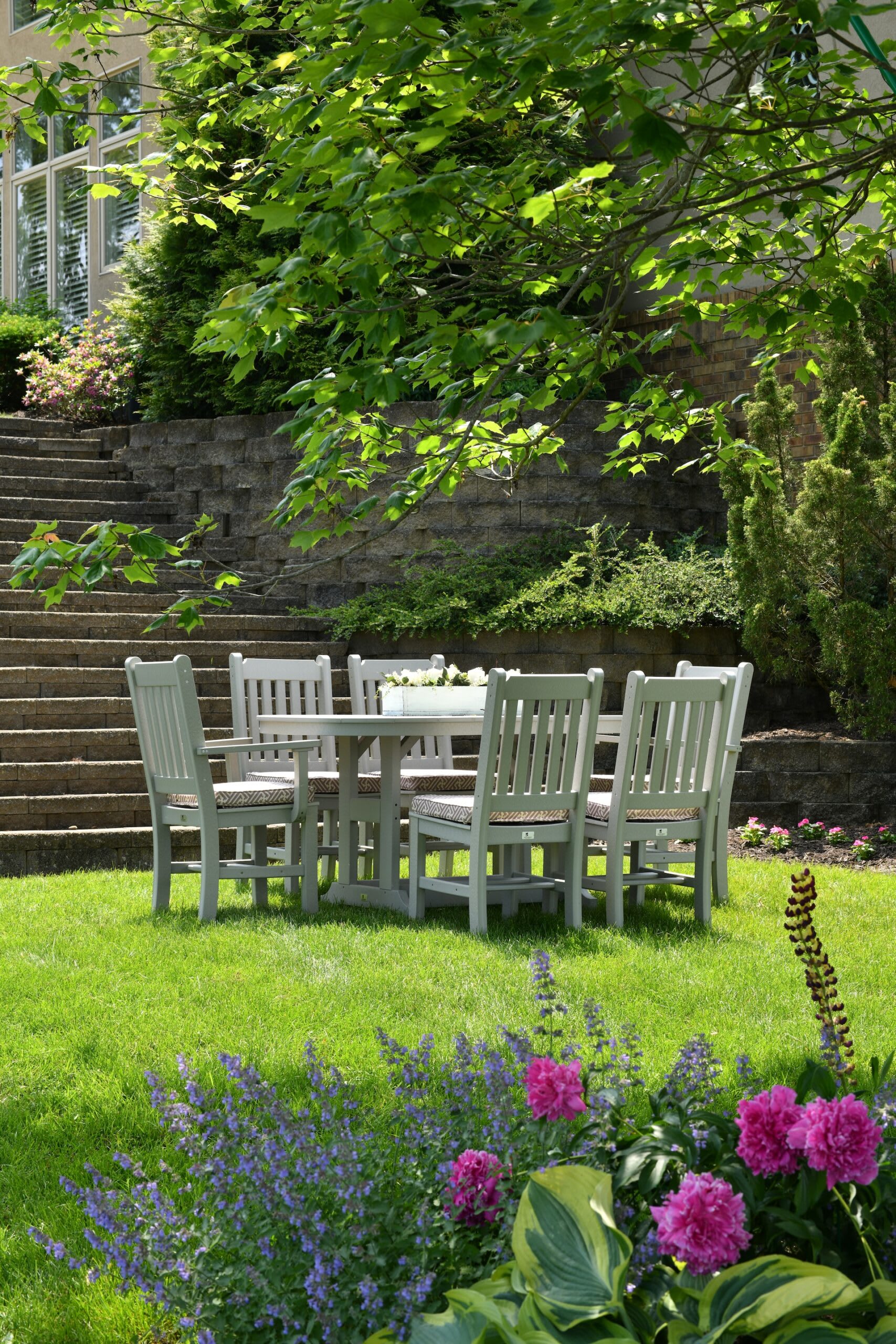 a set of white table and chairs in a summer garden