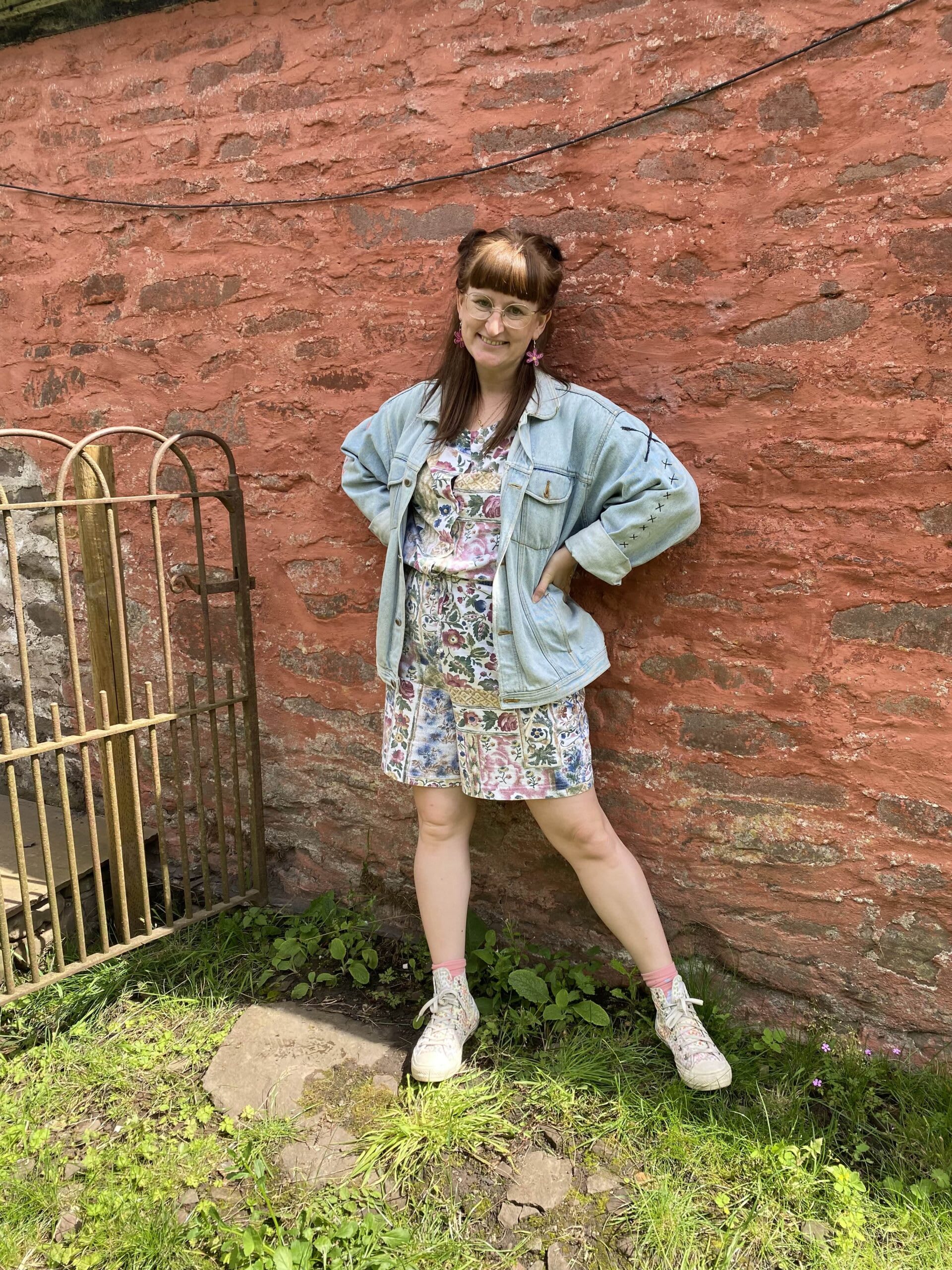 Ali wearing a vintage floral playsuit pared with a denim jacket, converse high tops and funky jewellery.
