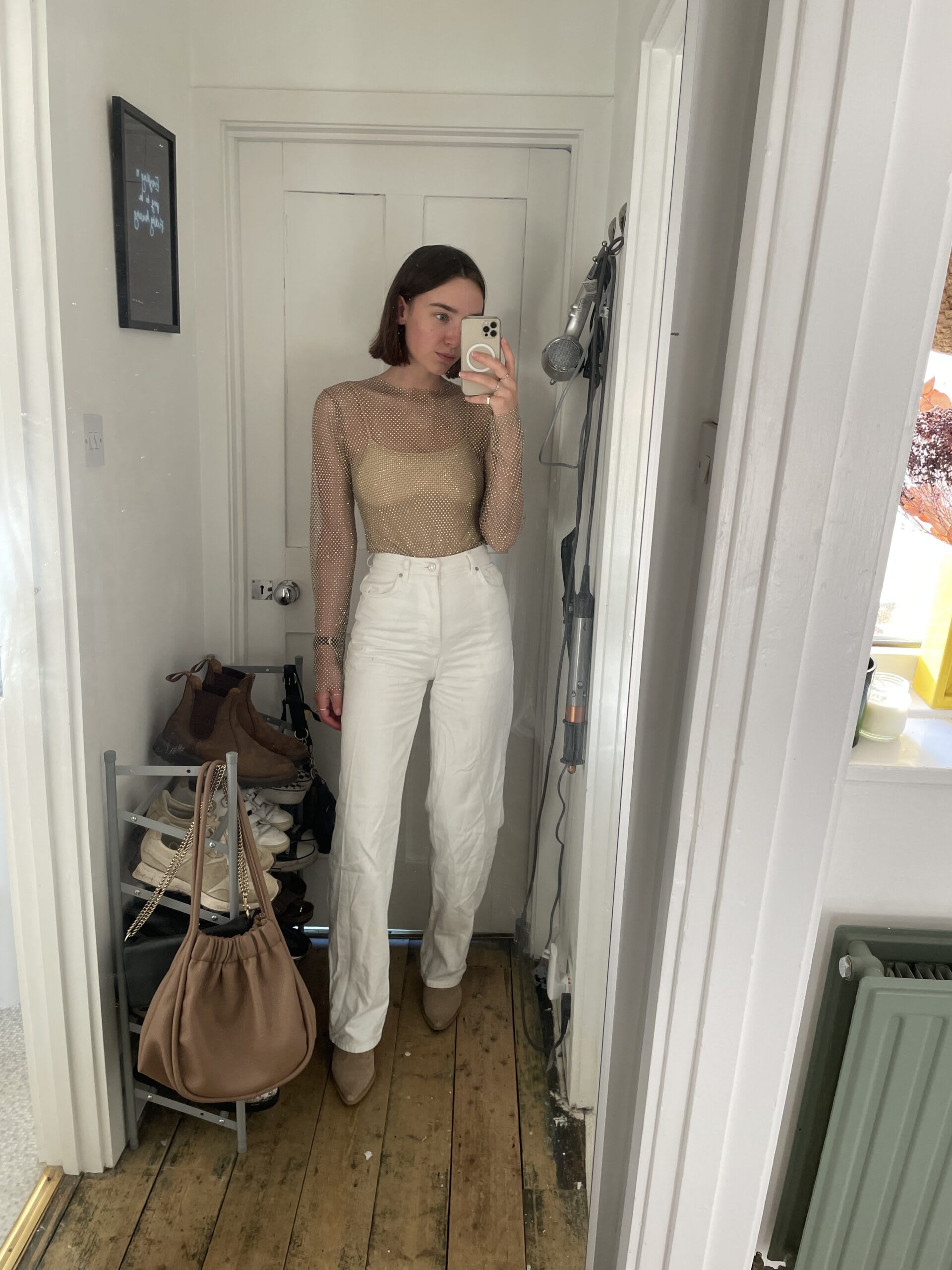 Iso wearing a statement mesh top with diamantés, paired with a nude leotard. white jeans and matching nude boots.