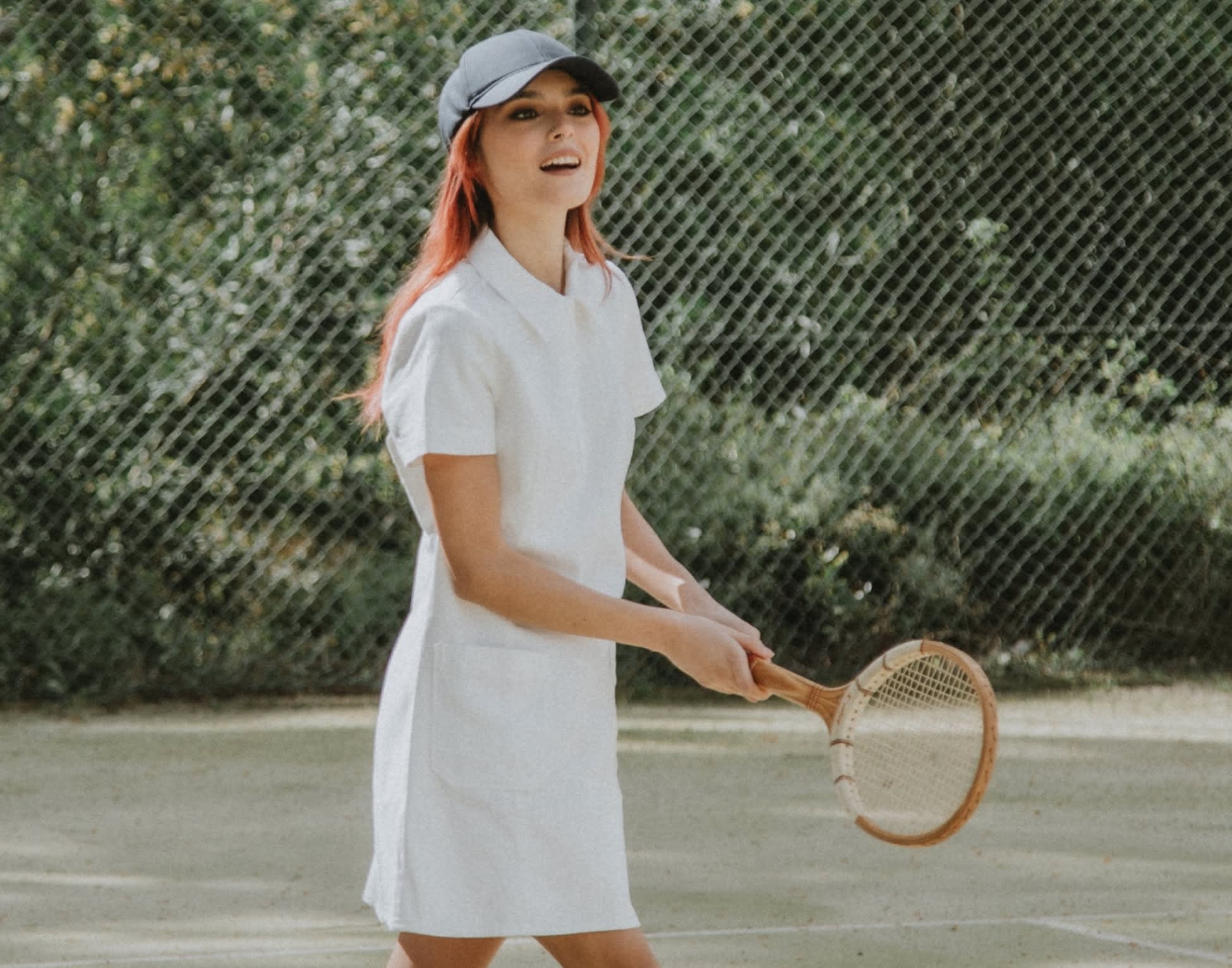 Woman playing tennis in a pre-loved white dress.