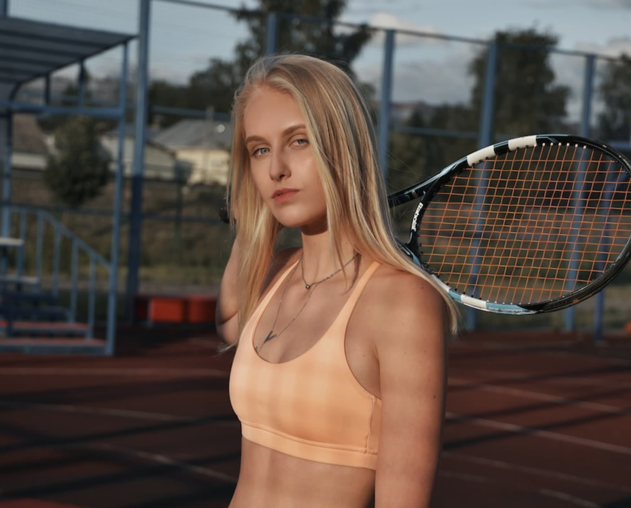 Woman playing tennis in a peach pre-loved sports bra.