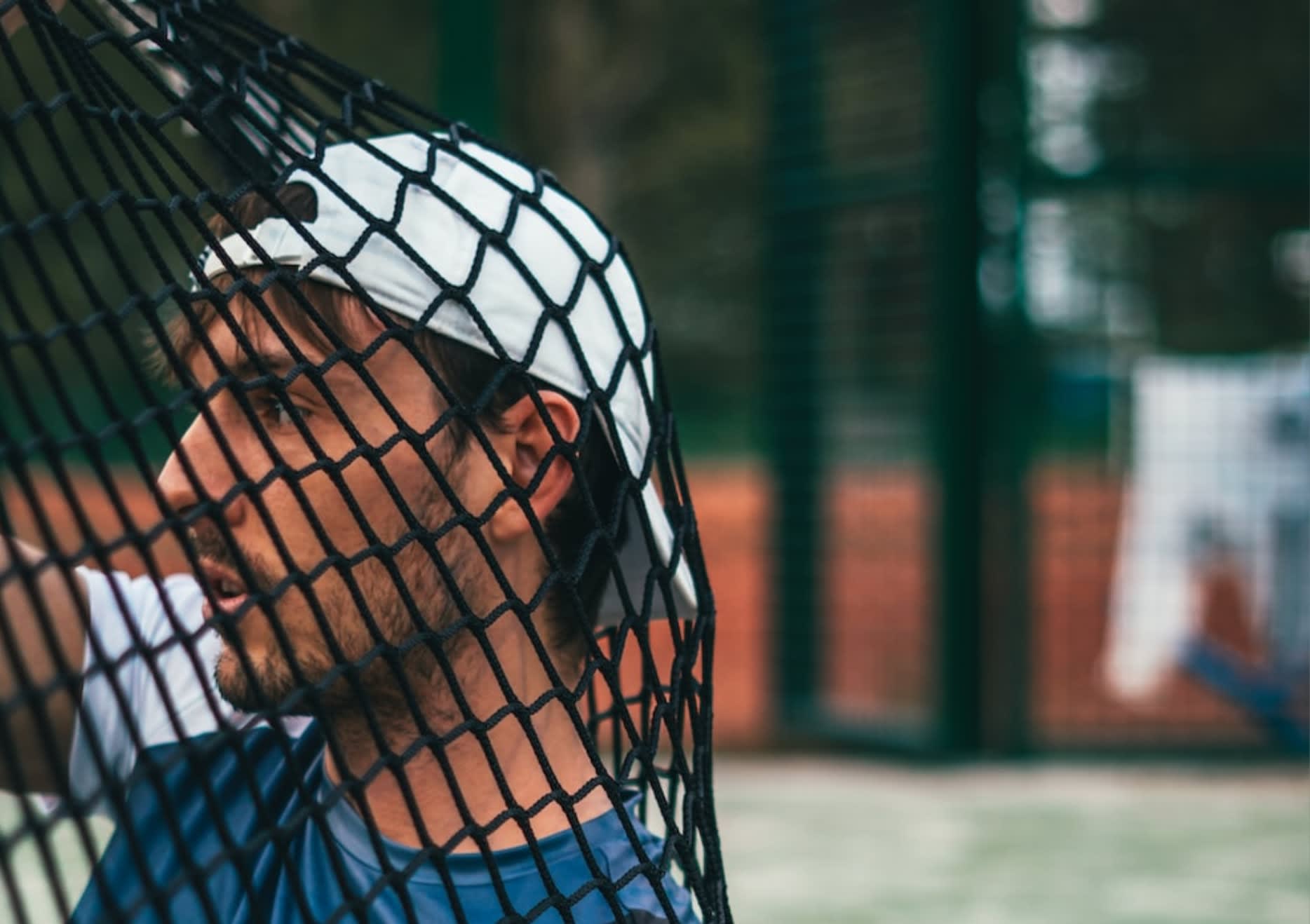 Man wearing a white cap on the tennis court.