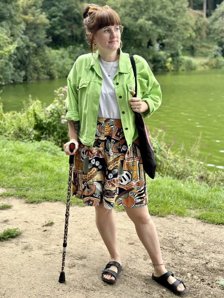 Little Splash standing wearing her look Lime Lady of the Lake in front of a mossy green lake
