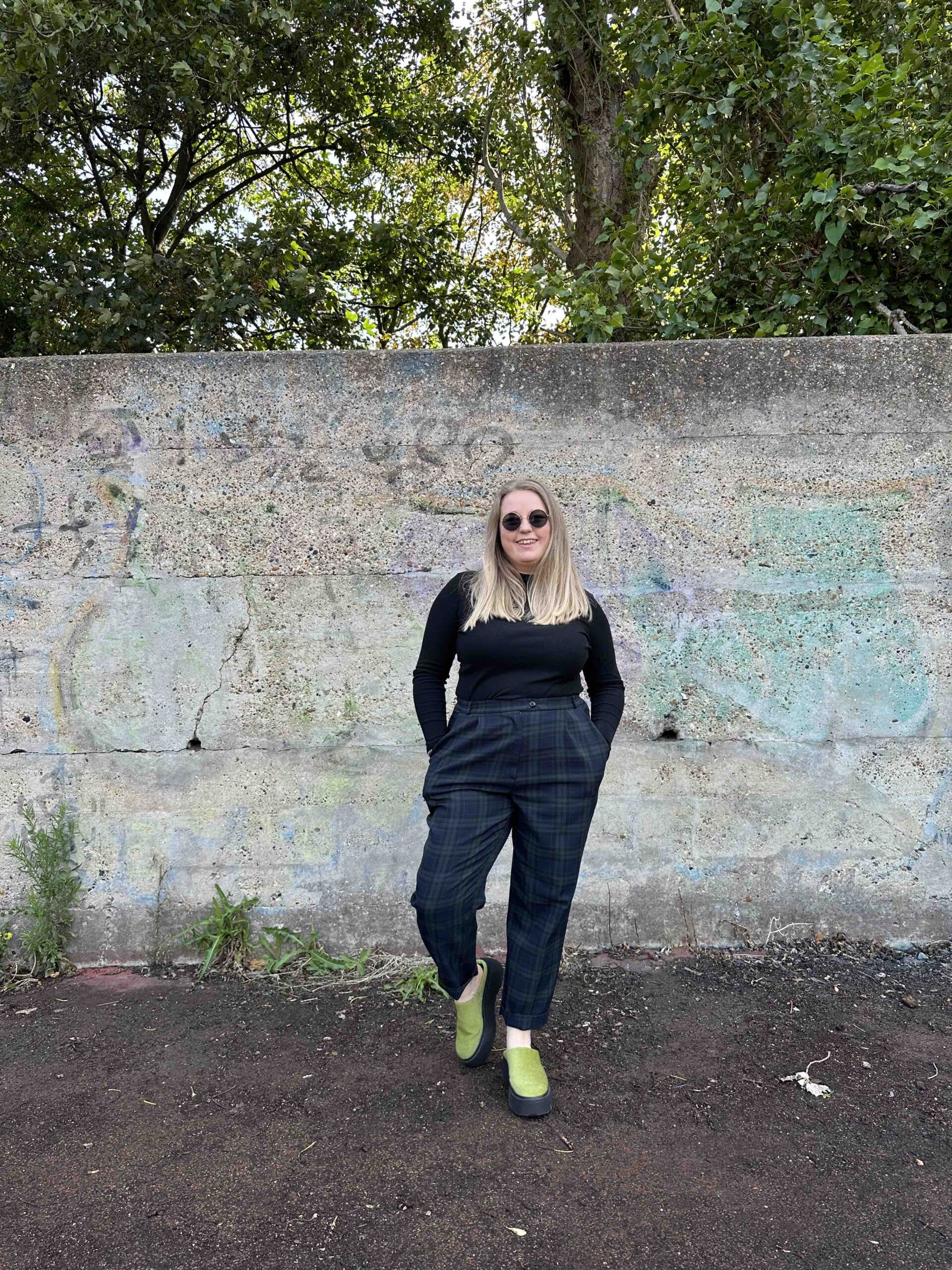 The Thrifty edit wearing her second hand look Wannabe Band manager, standing against a wall
