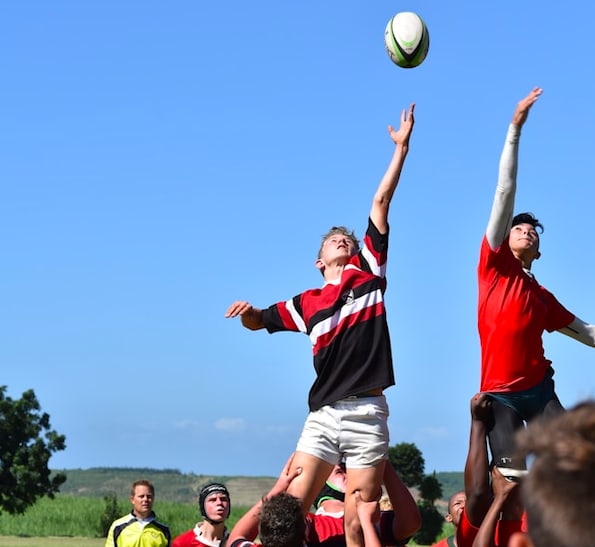 Boys jumping for Rubgy ball on a clear blue sky background