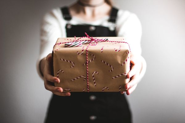 Girl holding out second-hand Christmas present in brown paper wrapping