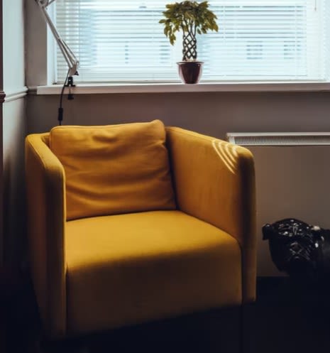 Used mustard arm chair in front of window