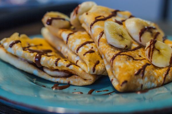 Plate full of crepes covered in chocolate and banana