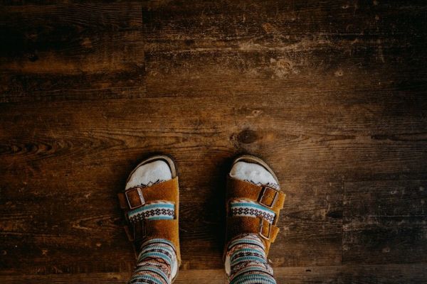 Person wearing socks and Birkenstocks on wooden floor