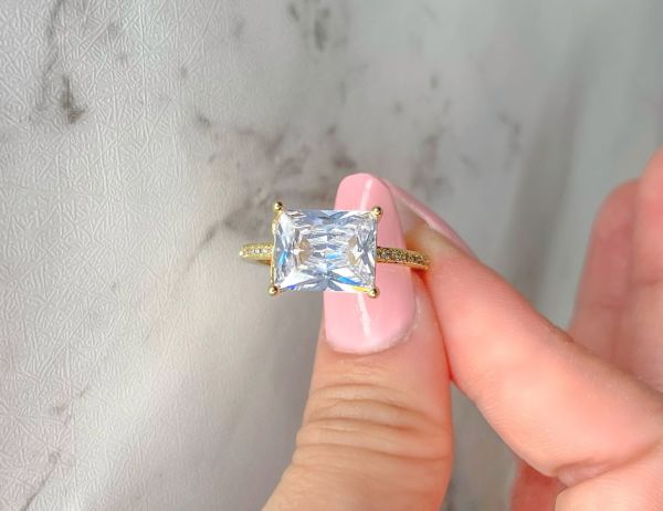 Woman holding a statement gold ring with big rectangle cut crystal