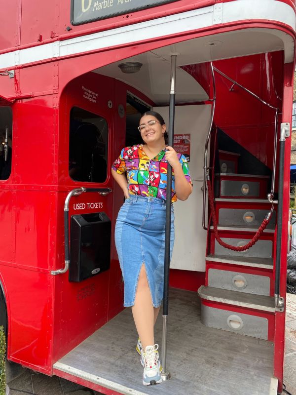 Amy Lorenz at Bthe back of a Longon bus. Wearing her pre-loved Disney Rainbow look