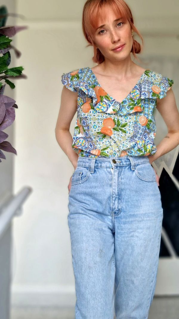 Jenny our pre-loved curator wearing blue mom jeans styled with a summery citrus print blouse.