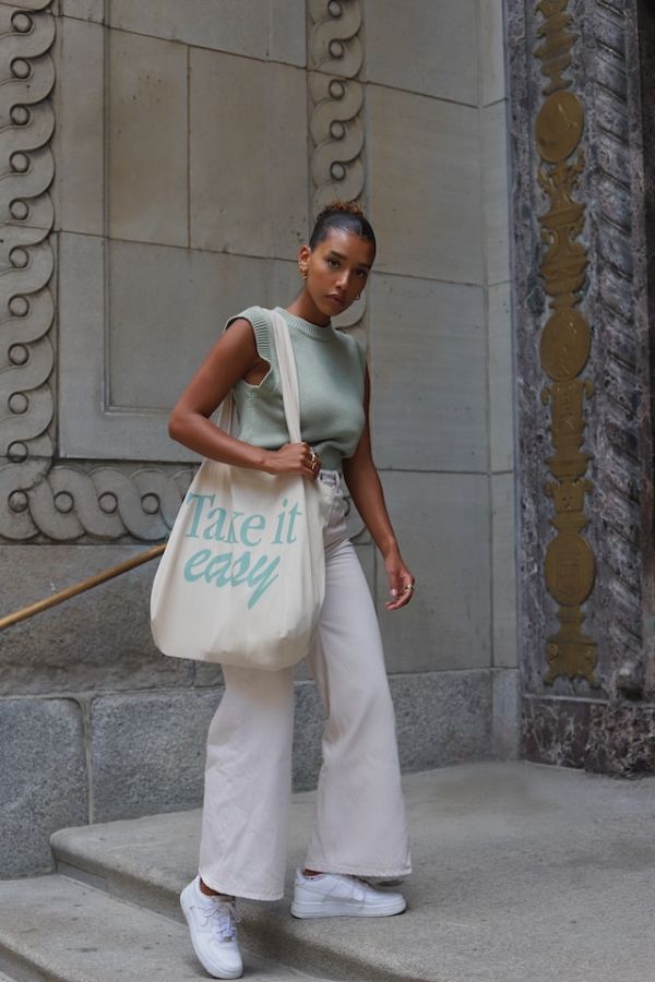 Woman wearing wide leg trousers on a step by a grand door