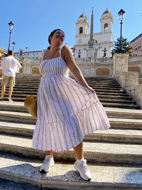 Amy Lorenz standing on some spanish steps while fanning out a white striped sun dress