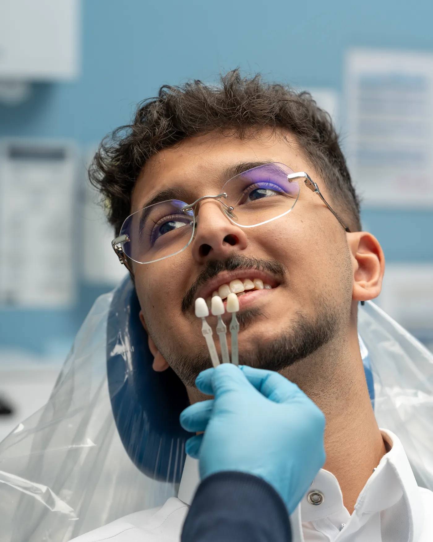طبيب أسنان في عيادتي يطابق درجة لون الأسنان مع ابتسامة المريض