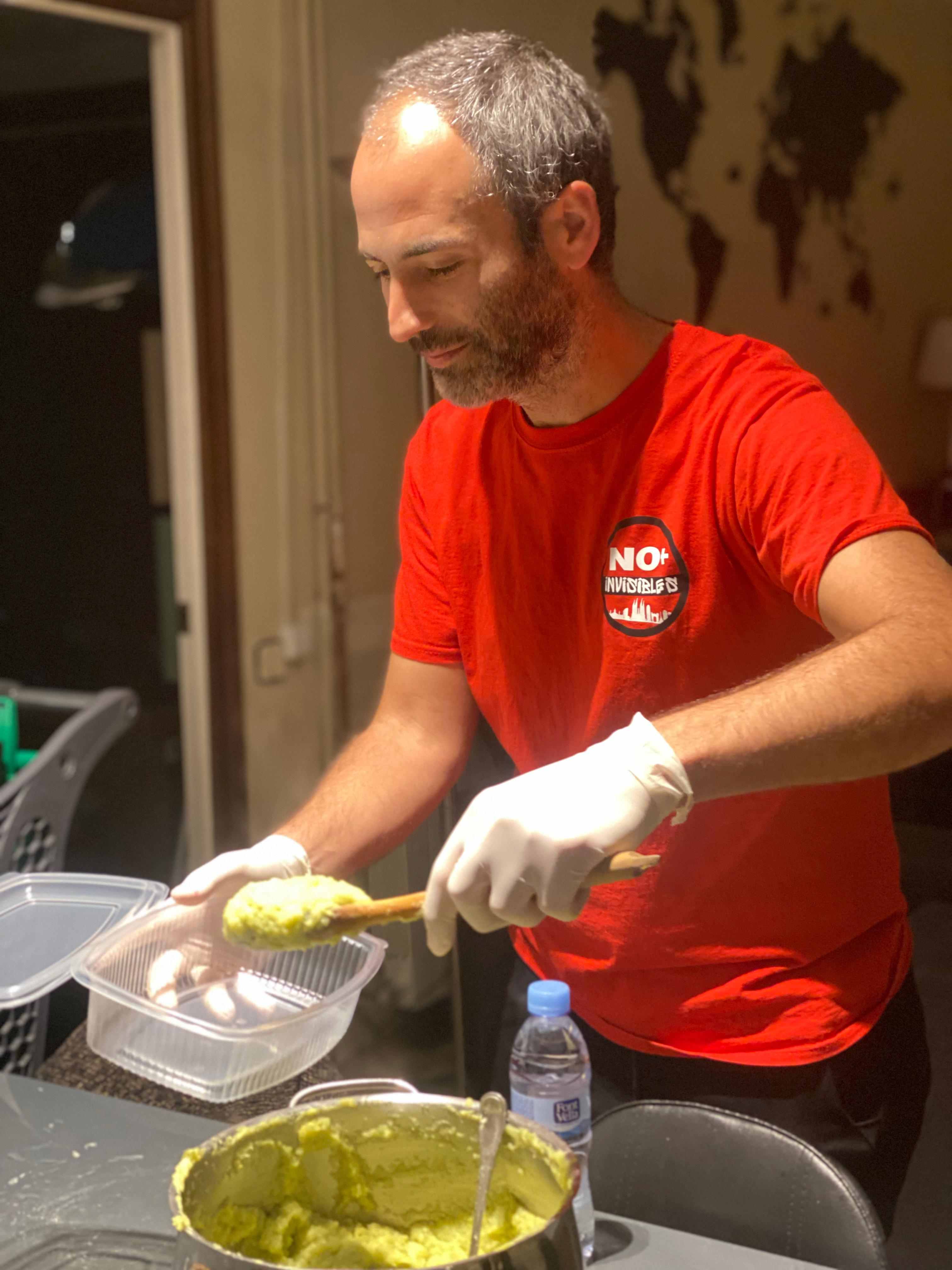 Voluntario cocinando platos nutritivos y equilibrados - preparación de 300 comidas semanales para personas sin hogar en Barcelona