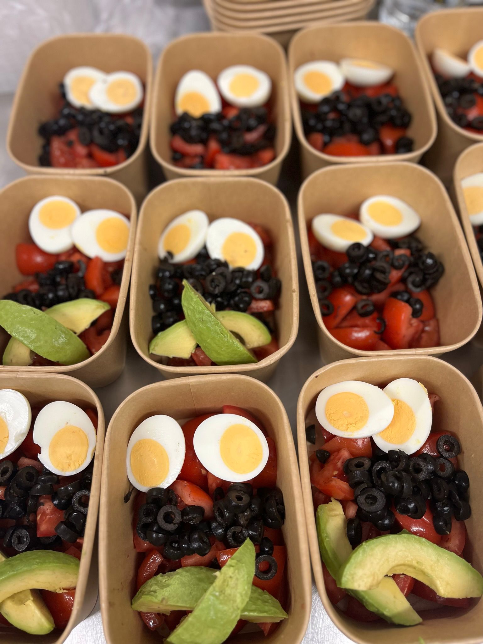 Ensalada nutritiva con huevo cocido, aguacate, tomate cherry y olivas - plato principal saludable preparado semanalmente para personas sin hogar