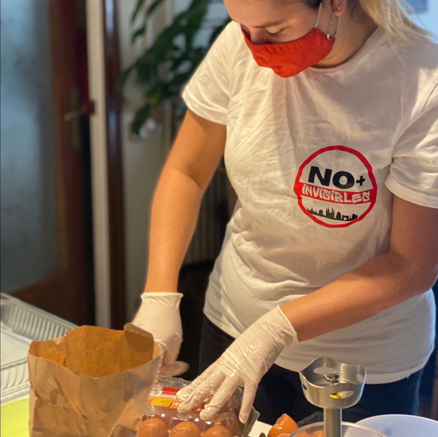 Voluntaria empacando kits de alimentación con alimentos frescos y productos de higiene para distribución semanal en Barcelona