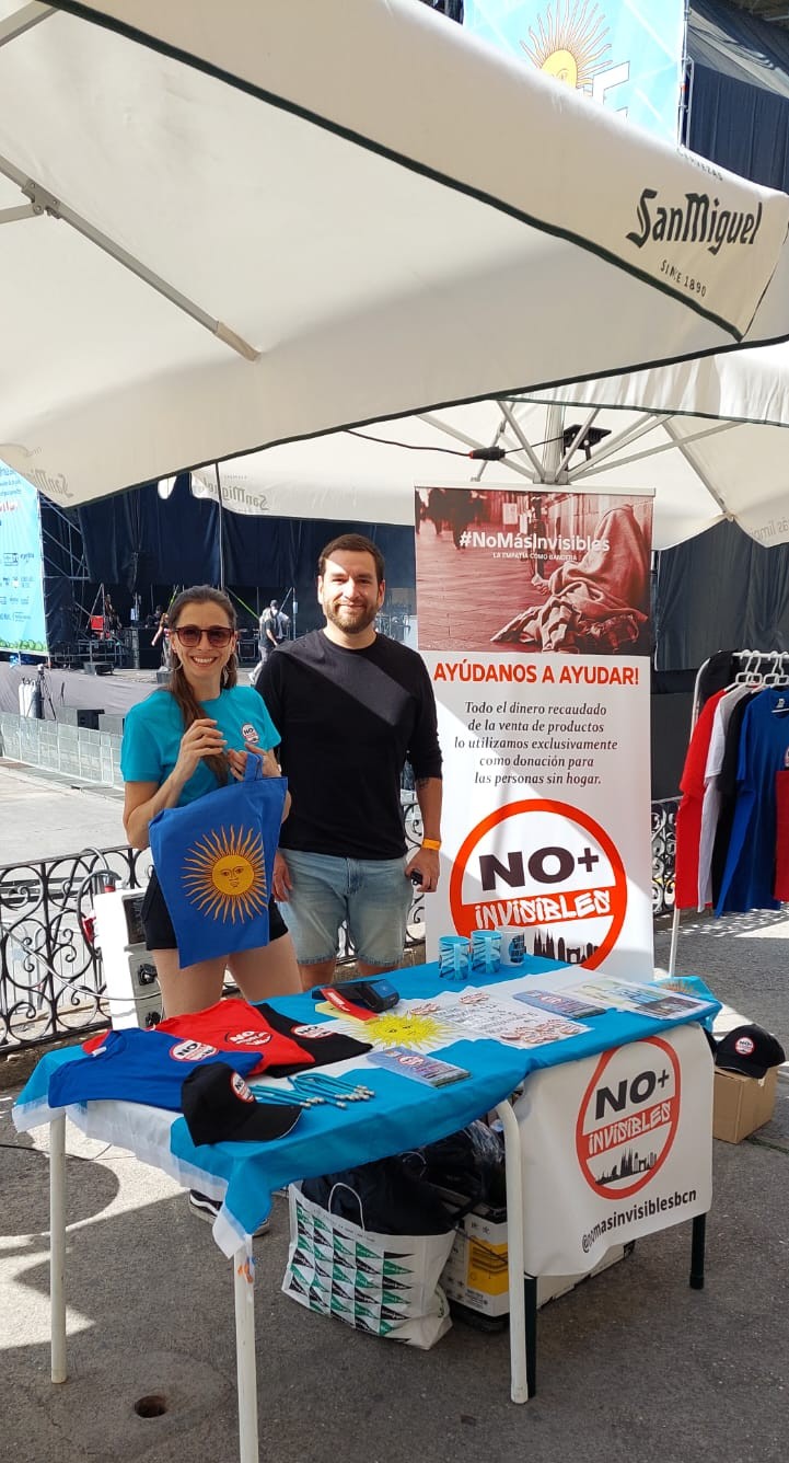 Stand de mercadillo solidario de No Más Invisibles en feria de Barcelona - voluntarios con merchandising exclusivo