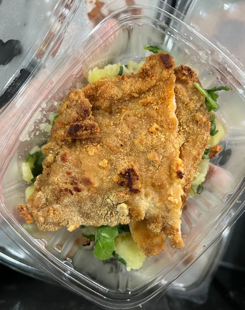 Milanesa de pollo crujiente acompañada de ensalada fresca - plato principal popular entre los beneficiarios