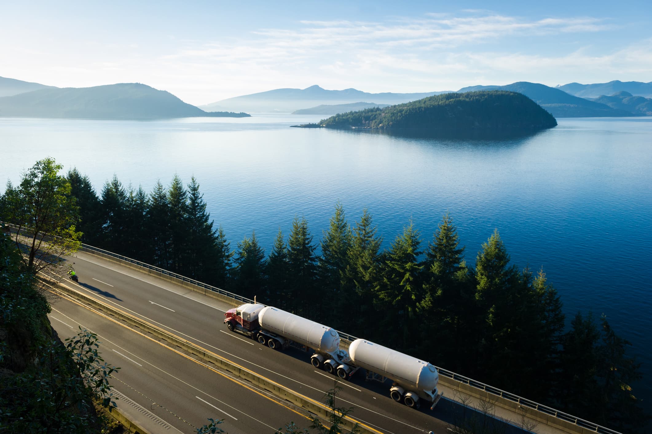 A truck driving on a road next to a large lake