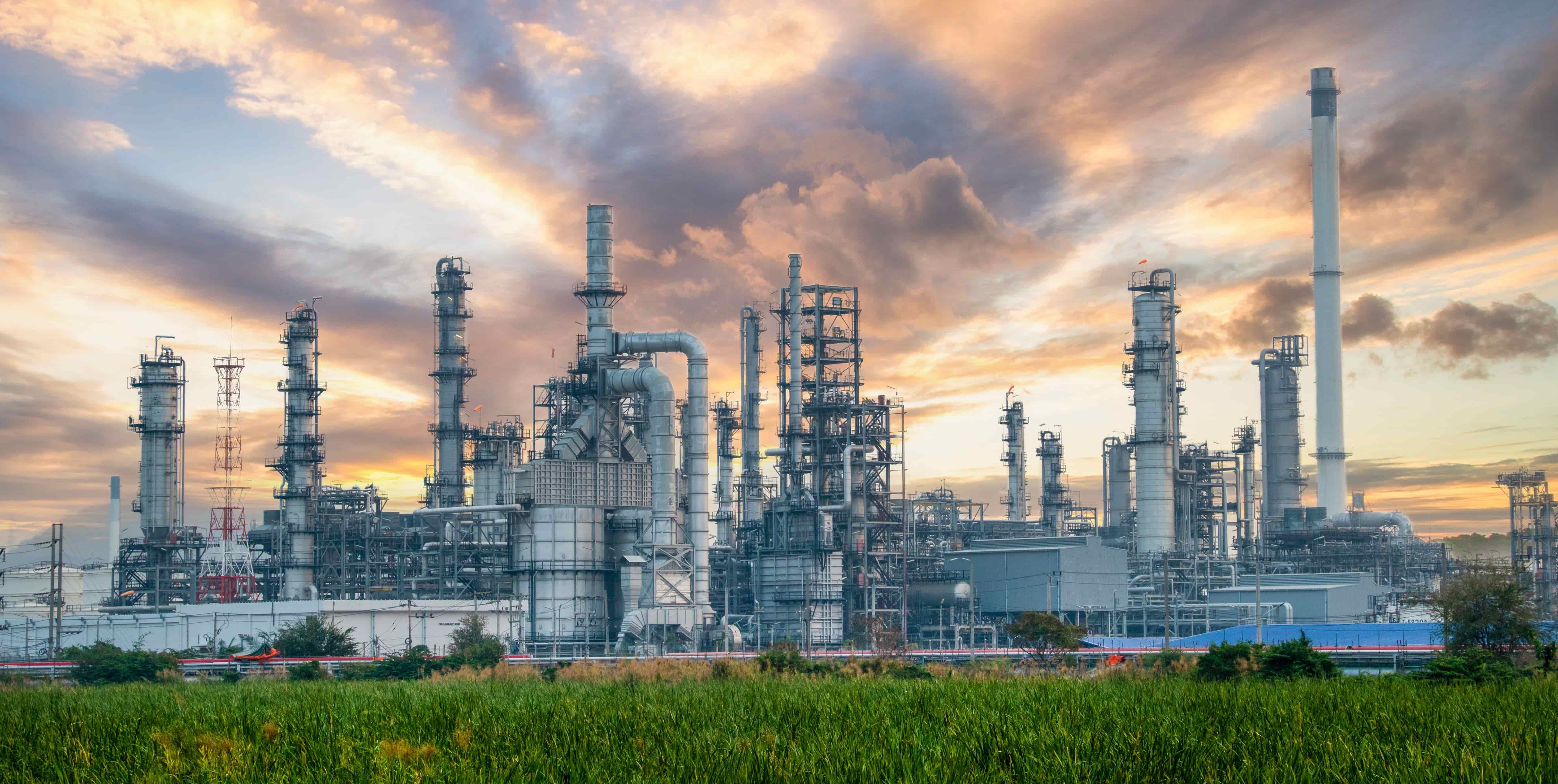 Chemical factory with sunset in the background and green grass