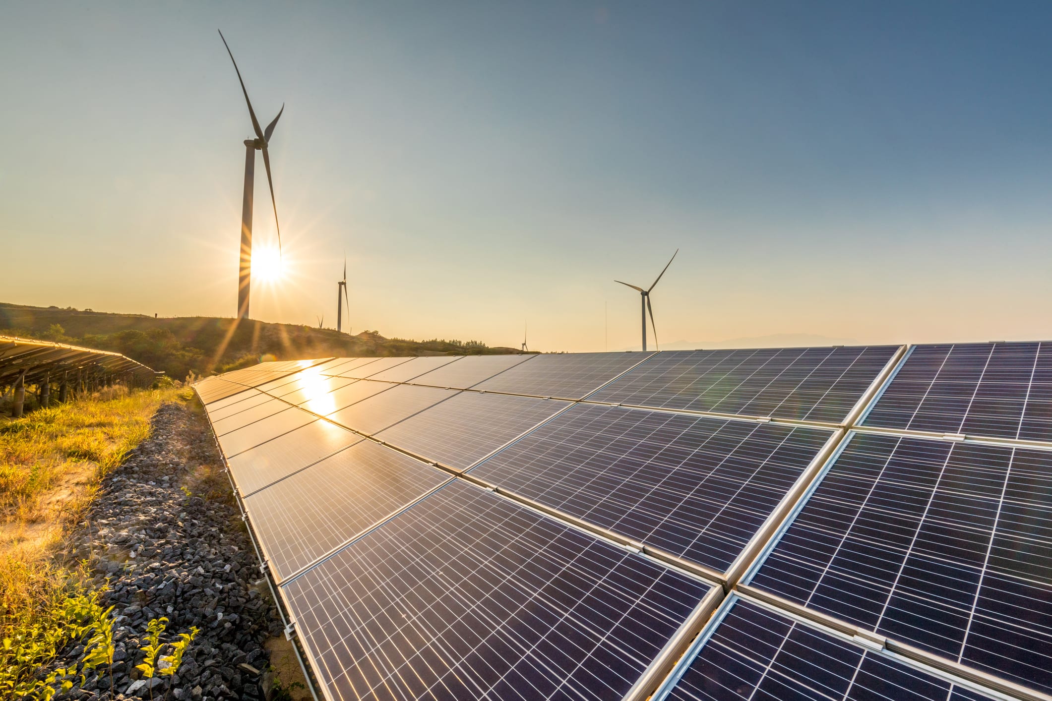 A solar panel and wind turbine in the sunlight