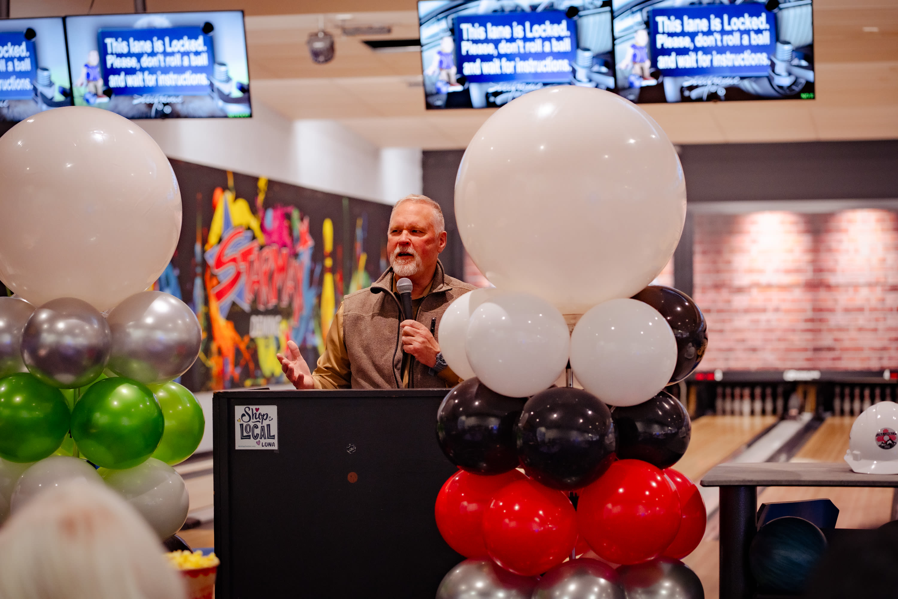 Man standing at podium with balloons to celebrate