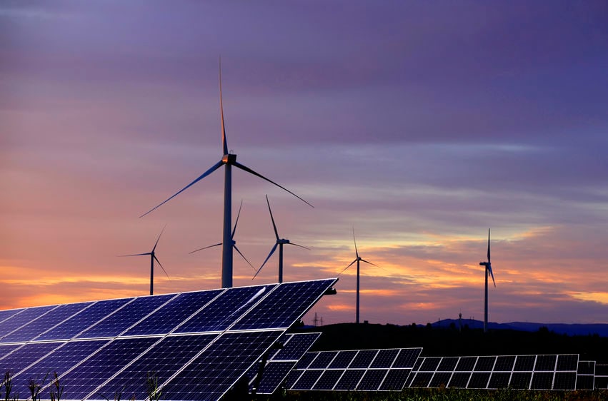 wind turbine and solar panels with sunset in the background