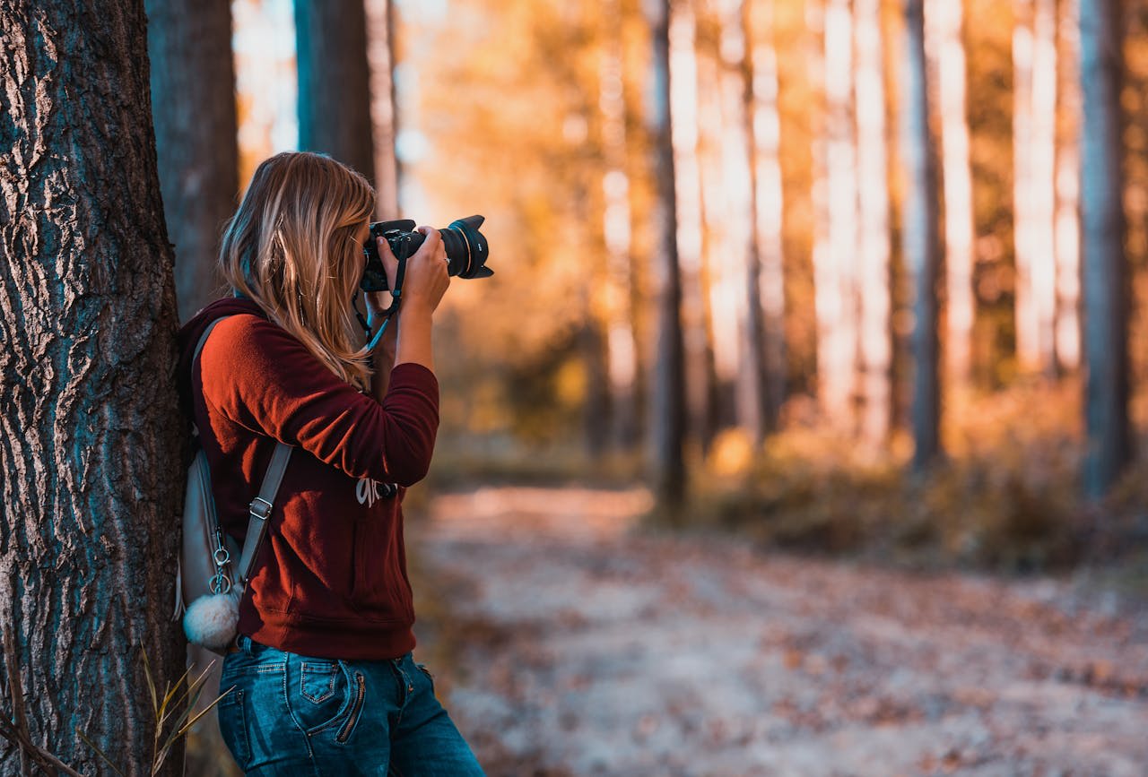 Photo by David Bartus: https://www.pexels.com/photo/woman-leaning-back-on-tree-trunk-using-black-dslr-camera-during-day-610293/