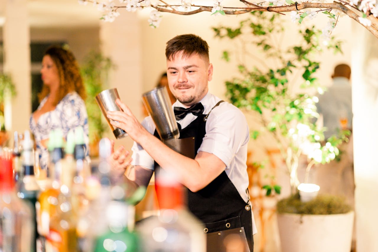 Photo by Tamilles Esposito: https://www.pexels.com/photo/a-bartender-making-a-cocktail-15513347/ Alt text: A man at a bar making a drink.