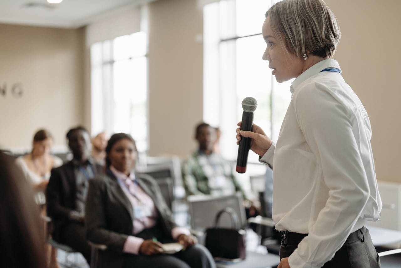 Photo by Pavel Danilyuk: https://www.pexels.com/photo/a-businesswoman-talking-on-a-microphone-8761534/
