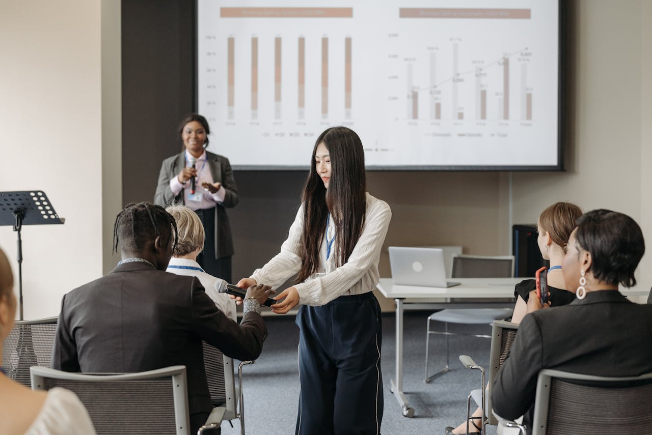 Photo by Pavel Danilyuk: https://www.pexels.com/photo/a-woman-in-white-long-sleeves-giving-a-microphone-to-the-participant-8761620/ 