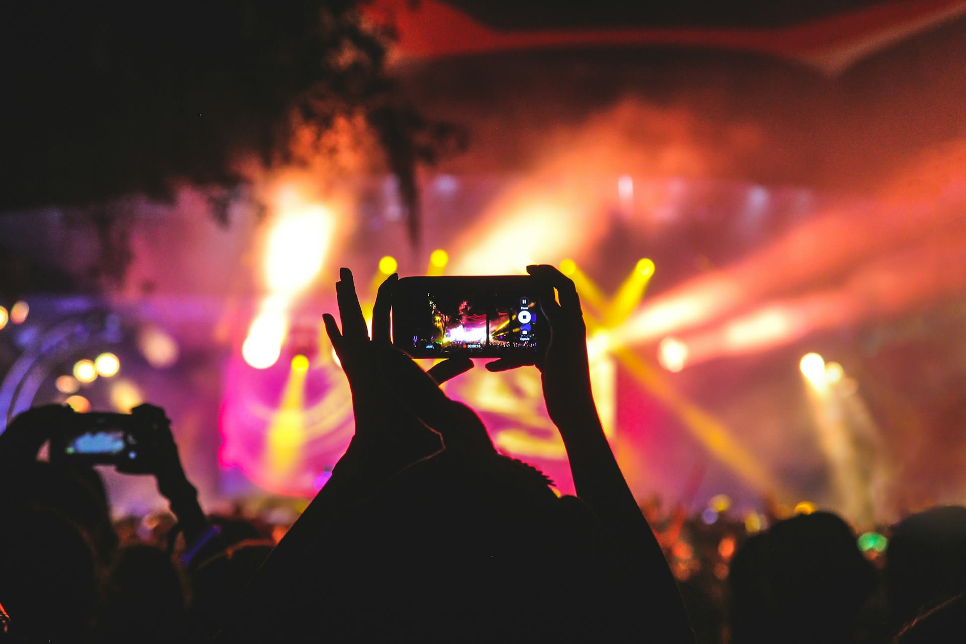 https://unsplash.com/photos/person-holding-smartphone-taking-video-of-a-concert-near-stage-with-lights-during-nighttime-JNuKyKXLh8U