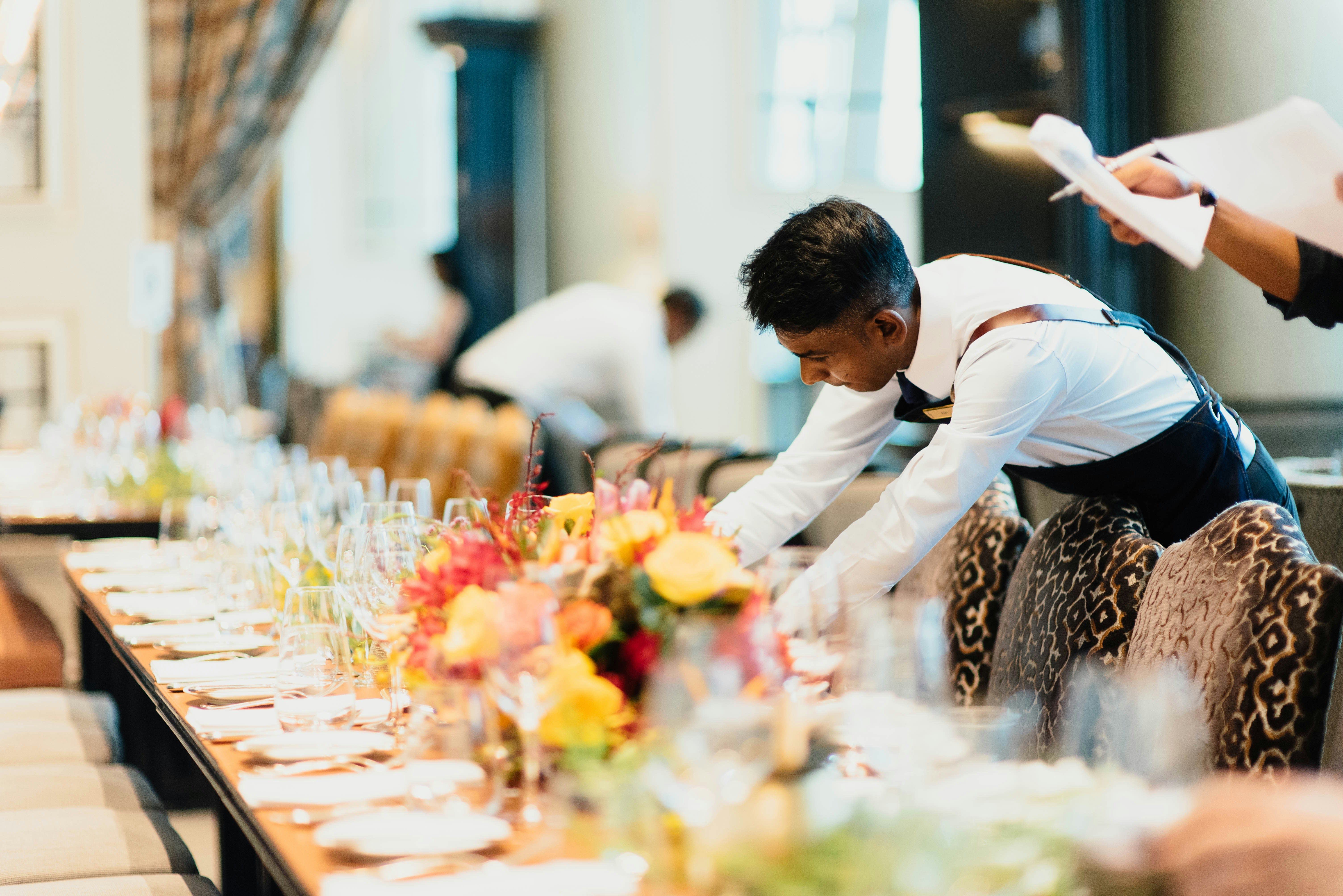 https://unsplash.com/photos/man-in-white-top-standing-next-to-table-OB7ol699Iww